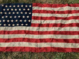 A worn American flag laid out on grass.