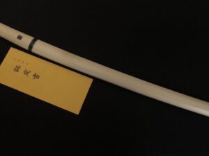 A white pen lying on a yellow sticky note against a black background.