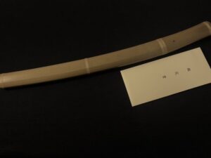 A curved blade with a wooden handle on a black background.
