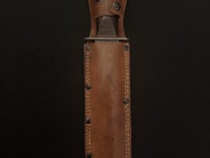 A worn leather sheath holding a knife against a dark background.