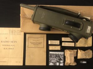 Vintage military communication gear and manuals laid out on a table.