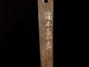 Close-up of a wooden object with engraved Japanese characters.