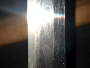 A close-up of a shiny metal blade reflecting bright light.