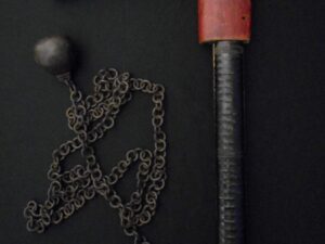 A rusty C-clamp with a tangled chain on a dark surface.