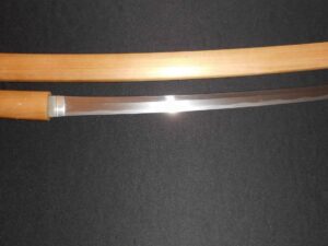 A traditional katana with a wooden scabbard on a dark background.