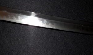 Close-up of a metal blade with engraved markings on a dark background.