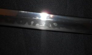 Close-up of a shiny metal blade with visible hamon pattern.
