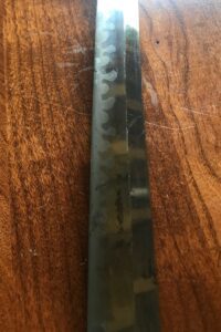 Close-up of a metal knife blade on a wooden surface.