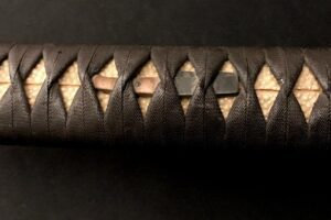 Close-up of a traditional Japanese katana handle with intricate wrapping.