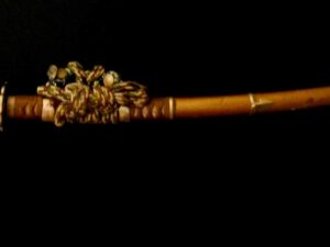 Intricately carved wooden flute with detailed floral designs on a dark background.