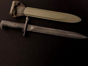 A knife with a sheath on a dark surface.