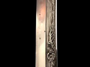 Intricately carved wooden panel with floral and geometric patterns in a vertical frame.