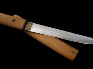 A wooden-handled knife with a polished blade on a black background.