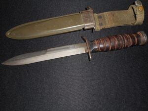 A military-style knife with a leather handle and its sheath.