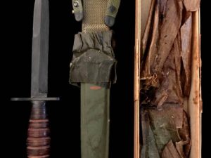 A military combat knife with sheath and worn cloth wrapping.