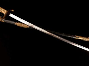 A traditional wooden didgeridoo with a decorated mouthpiece on a black background.