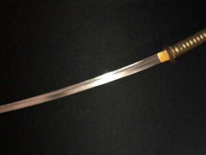 A close-up of a curved sword with a wooden handle on a black background.