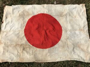 Worn Japanese flag with a red circle on a white background.