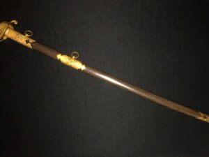 Antique sword with intricate golden handle against a dark background.