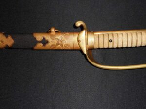 Close-up of an antique sword handle with a protective guard and worn grip.