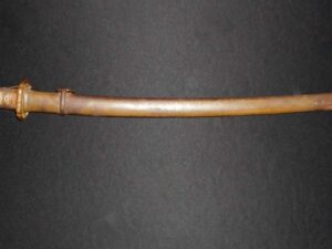 A wooden walking cane with a curved handle on a dark surface.