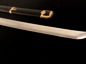 A katana sword partially sheathed in a black scabbard with gold accents.