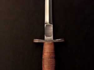 A vintage hunting knife with a leather-wrapped handle against a dark background.