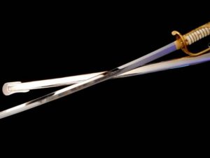 Two metallic kitchen tongs crossed on a black background.