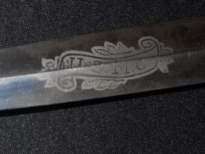 Close-up of a metallic blade with intricate engraved text and design.