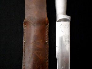 A vintage fixed-blade knife with a leather sheath on a black background.