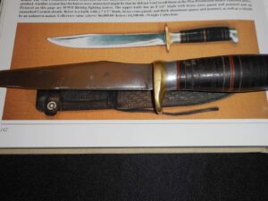 Vintage hunting knife with leather sheath and stacked handle.