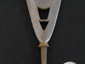 Close-up of a metallic spear tip with a coin for scale.