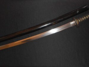 A polished katana blade with a dark handle on a black background.