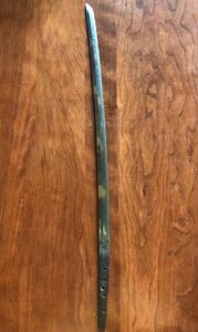 A curved sword with a dark handle and blade on a wooden surface.