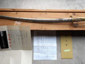 An old sword displayed with handwritten letters and a certificate.