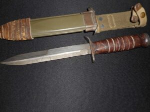 A combat knife with a leather-wrapped handle and its sheath.