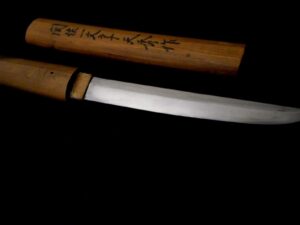 A close-up of a traditional Japanese katana with wooden sheath and inscriptions.