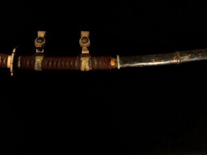 An ornate, vintage dagger with a decorated sheath against a black background.