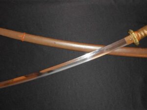 A sword with a wooden sheath on a dark surface.