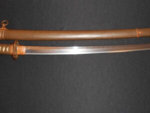A traditional Japanese katana with its wooden sheath on a dark surface.